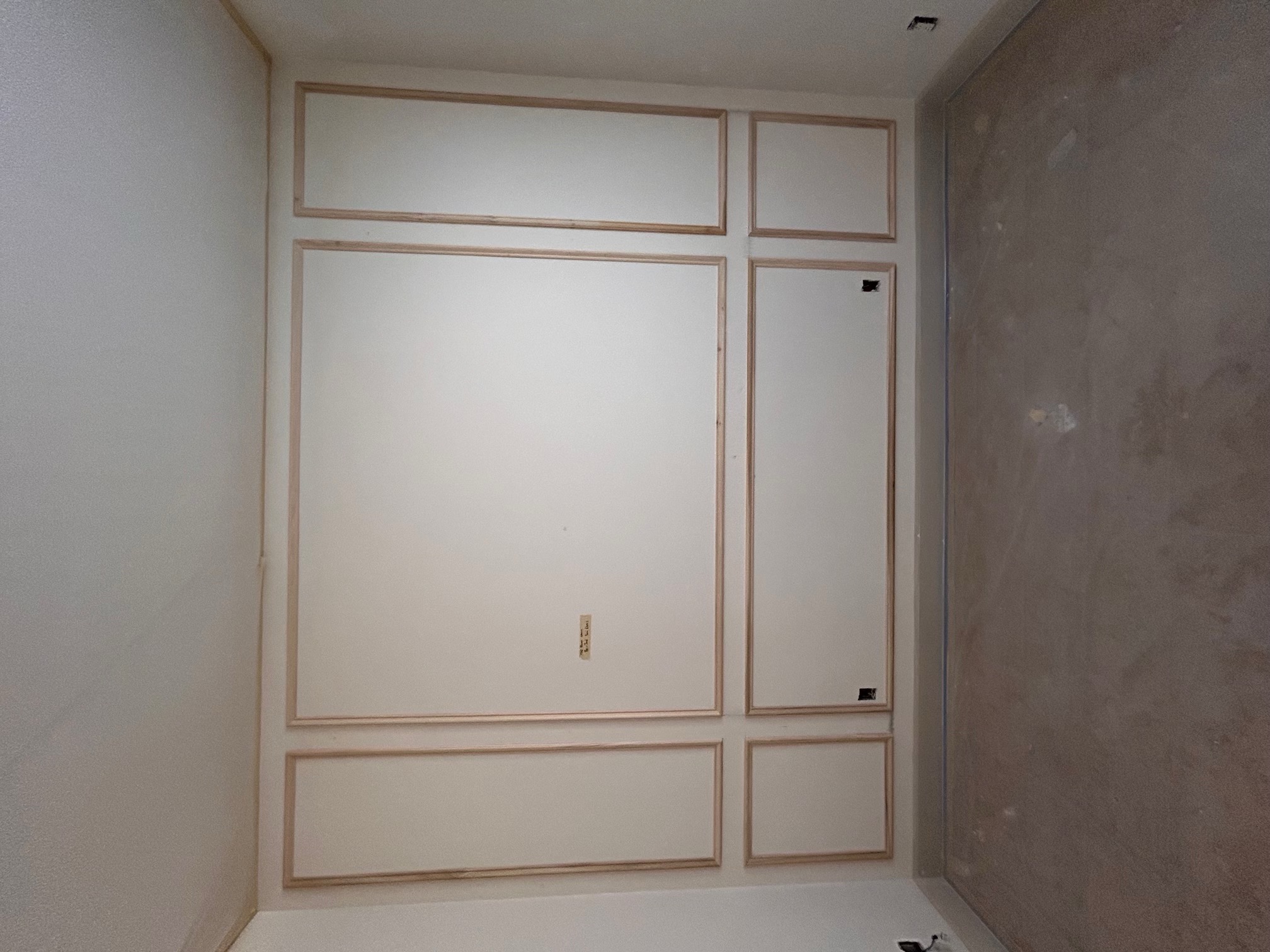 Decorative rectangular wall moulding installed in an unfinished room before paint